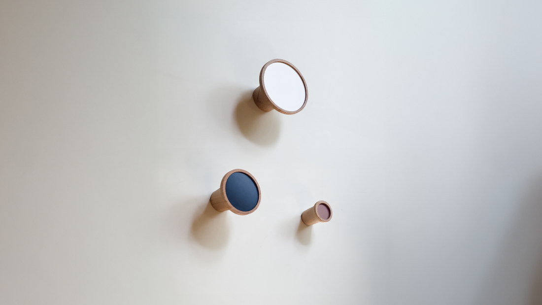 Crochets muraux en bois avec finitions colorées, design minimaliste et écoresponsable pour décoration intérieure.